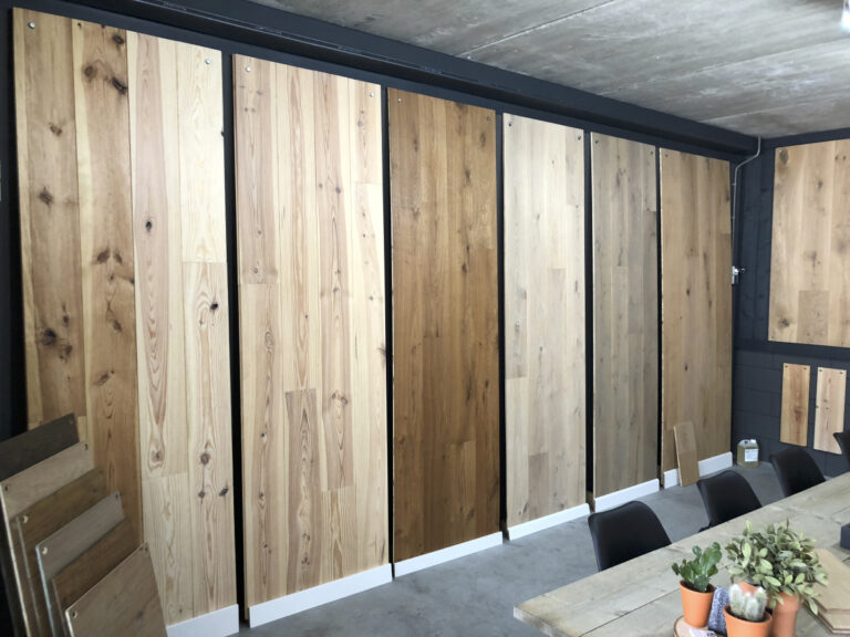 Houten vloerdelen in verschillende kleuren aan een showroomwand